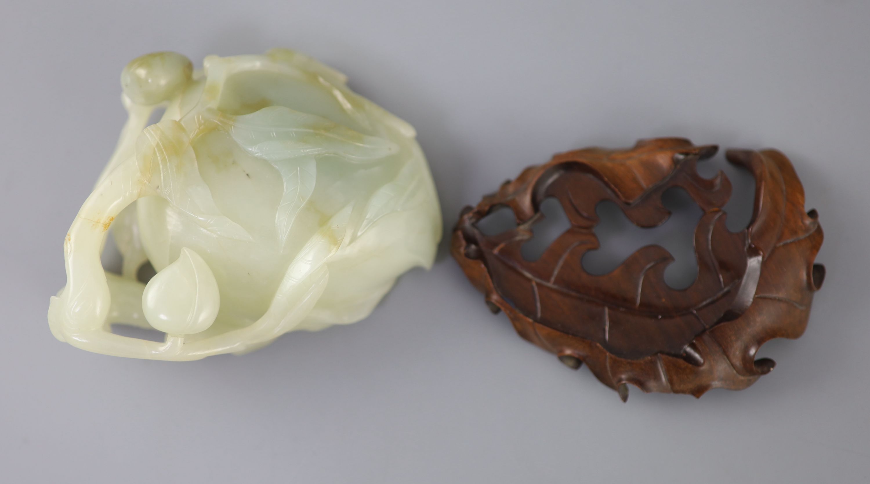 A Chinese pale celadon jade peach brush washer, 17th/18th century 11.3cm at widest point, wood stand